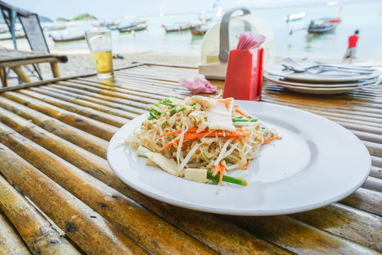Pad Thai on white dish at outdoor restaurant on the beach