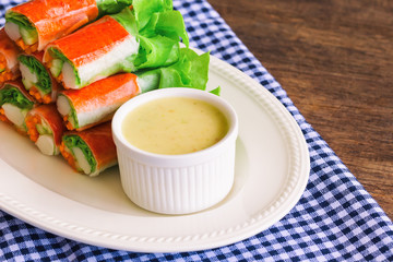 Fresh spring rolls with fresh vegetable and crab stick served with spicy salad cream dipping sauce. Rolls salad or fresh spring roll on white plate, healthy delicious food for appetizer or meal.
