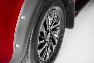 Front wheel of red car, black alloy wheels.