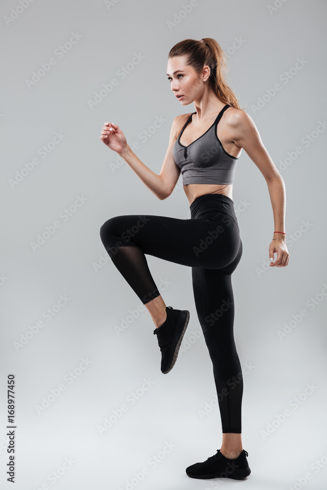 Wall mural Full length portrait of a young woman in sportswear posing