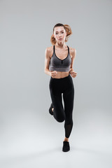 Fototapeta na wymiar Full length portrait of a young woman in sportswear running