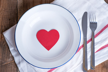 Concept diet and weight loss. Empty plate with red paper heart in the middle of the plate 