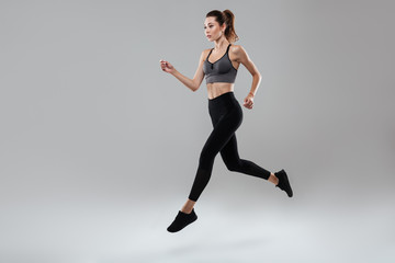 Side view full length portrait of a young fitness woman running