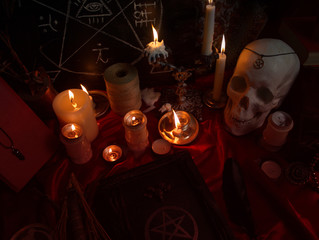 Witchcraft composition with human skull, burning candles, magic book, amulets and pentagram symbol....