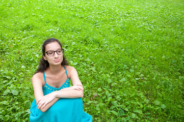 Girl in a green dress is sitting on lawn