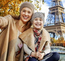 smiling mother and daughter tourists taking selfie in Paris