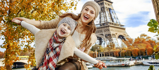 Obraz na płótnie Canvas smiling mother and daughter travellers having fun time in Paris
