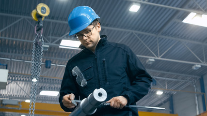 Factory worker is making a quality control of a metal detail with a measuring tool.