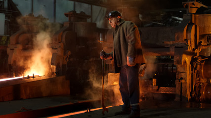 Heavy Industry Worker Doing Quality Control in Foundry. Rough Industrial Environment. Wide Shot.