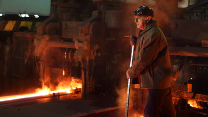 Heavy Industry Worker Doing Quality Control in Foundry. Rough Industrial Environment. Wide Shot.