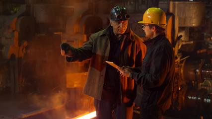 Engineer and Worker Have Conversation in Foundry. Engineer Using Tablet. Rough Industrial...