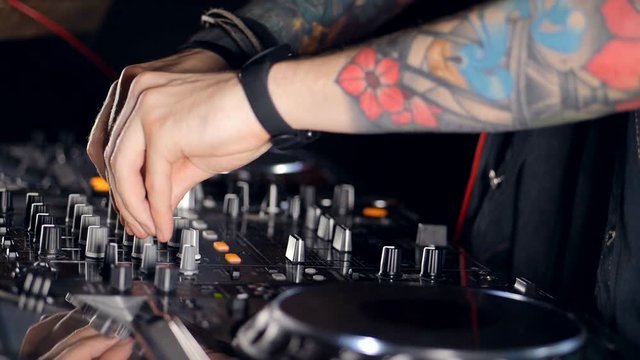 A side view on a DJs hands creating music. 