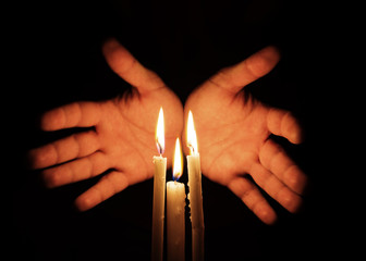 Mani intorno a candele accese