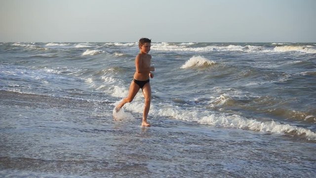 Smiling boy running at the sea surf