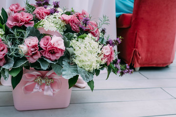Rustic wedding composition with pink and white different flowers and greens in a pink bucket on the aged wooden floor. Artwork. Close-up.