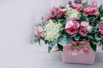 Leaflet. Rustic wedding composition with pink and white different flowers and greens in a pink bucket on the aged wooden floor. Artwork. Close-up.