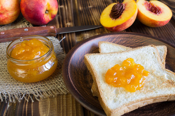 Bread toasts, nectarine jam and fruit on the brown wooden background 