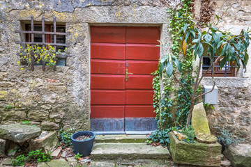 Red entrance door to a house on stone street in Istria, Croatia, Europe.