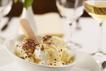 Egg white with vanilla mousse arranged on a plate, Wineglass in background, Traditional dessert in elegant setting, Selective focus with soft light