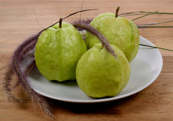 guava fruit in white plate on wood