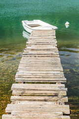 A wooden pier leading to a small anchoring boat.