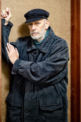 Portrait of a mature man with a white beard and a cap on the head. He could be a sailor, a worker, a docker, or even a gangster or a thug. He has a penetrating gaze.