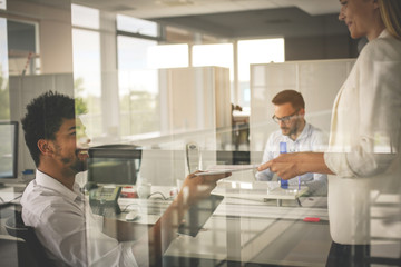 Three business people working in office. Two business people holding document.