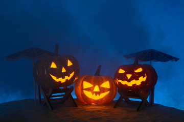 Carved pumpkins in composition on sand