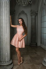 Portrait of Beautiful romantic lady. Beautiful young woman in a pink lacy dress, in a vintage luxury grey interior. long curly hair, fashion makeup