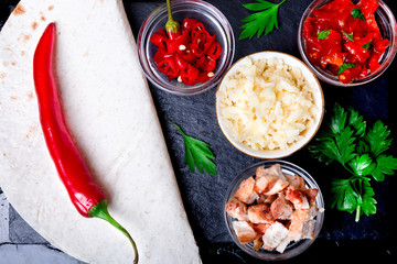 Ingredients for mexican quesadilla with salsa on black slate stone plate. Top view.