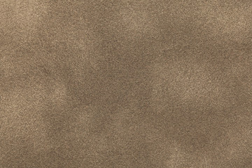 Background of light bronze suede fabric closeup. Velvet matt texture of sand nubuck textile.