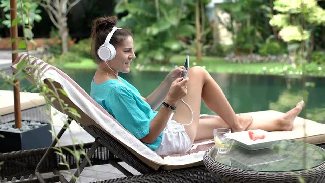 Woman losts game while playing on tablet and sitting next to the swimming pool, steadycam shot
