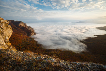Dramatic sunset landscape in yellow autumn high mountains over clouds. Beautiful scenery of sky