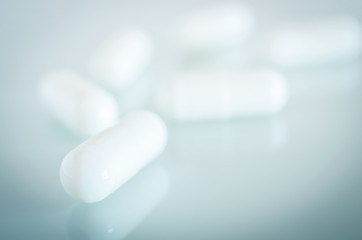 White medical capsules lie on the mirror surface