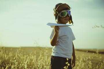 Vacation, Boy playing to be airplane pilot, funny guy with aviator cap and glasses, carries in his hand a plane made of paper