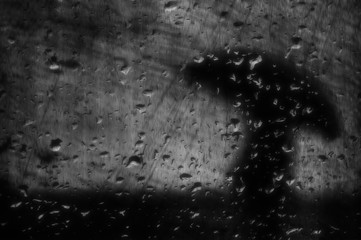 raindrops on window with person with umbrella and grungy textures