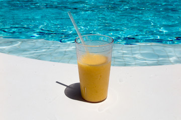 fruits cocktail at the edge of a resort pool. Concept of luxury vacation. Outdoor pool background