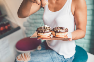 Young woman enjoying in delicious glazed and decorated donuts