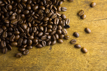 Blank paper cup with good roasted coffee beans dropped on thick wooden table  