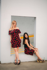 Beautiful girls posing for the photographer. Two sisters in black and red dress. Smile, sunny day.