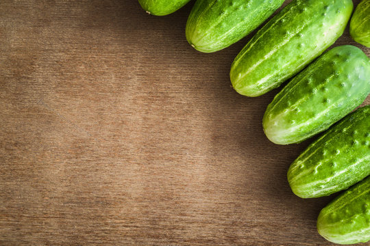Green cucumbers on the wooden table. Healthy eating and lifestyle. Rustic atmosphere. Harvest background. Top view.