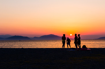 Silhouetted shot of sunset with people by the beach