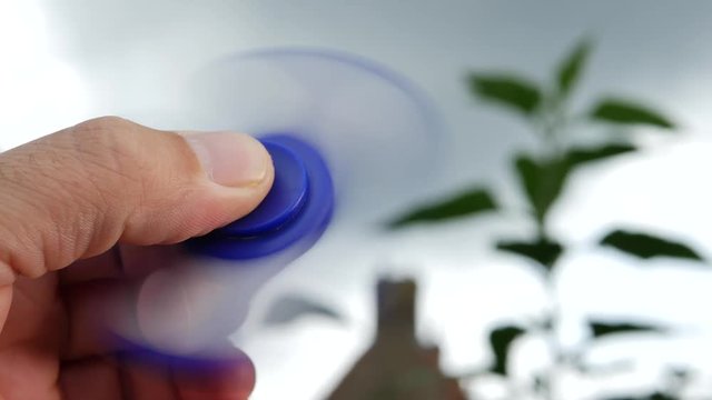Hand holding popular fidget spinner toy on sky background 