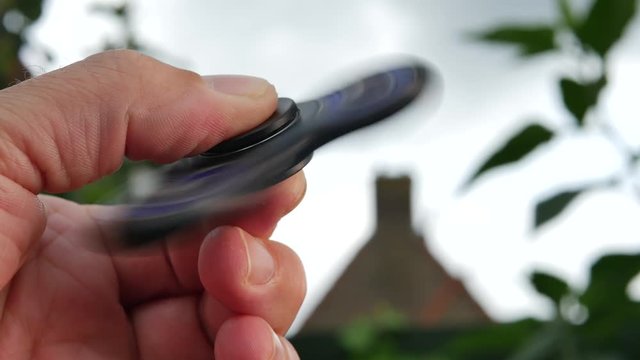 Hand holding popular fidget spinner toy on sky background 