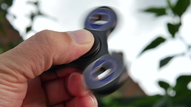 Hand holding popular fidget spinner toy on sky background 