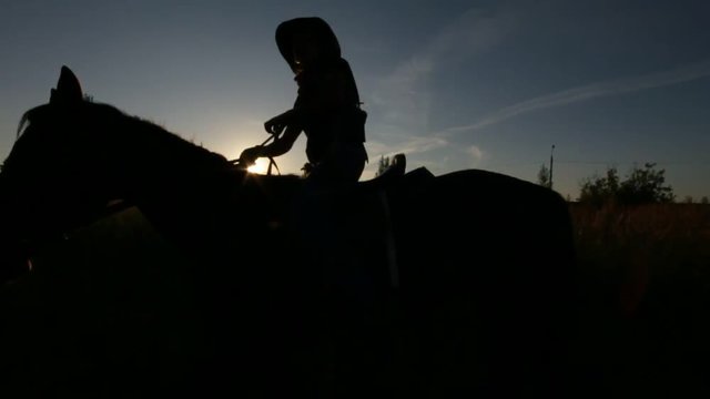 Horse rider walking at sunset - silhouette shot, slow-motion