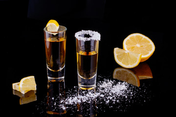 Gold Mexican tequila with salt on black background. Alcoholic drink concept. selective focus