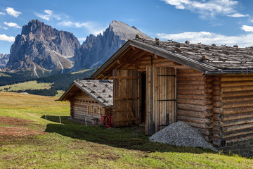 Obraz premium Kilka chat górskich na łąkach w tle Dolomitów