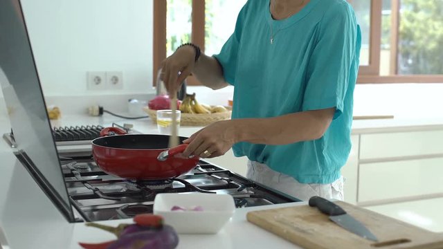 Woman standing in the kitchen and cooking dish, steadycam shot
