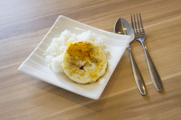 Fried egg with rice on whit plate and cutlery